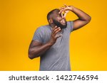 Small photo of Afro american man isolated against yellow background smelling something stinky and disgusting, intolerable smell, holding breath with fingers on nose. Bad smells concept.