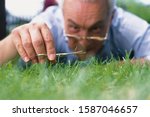 Small photo of Man cutting grass with nail scissors