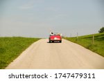 Small photo of Couple driving convertible in countryside