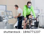 Sports scientist recording the performance of a cyclist working out on the exercise bike