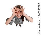 Small photo of Funny girl making finger glasses. Playful and impish mood. Top view, full length portrait.