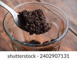 Small photo of Someone scoops out coffee grounds that have settled at the bottom of a cup or glass. Waste from coffee drinks.