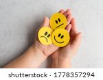 Kids emotions. Kids Hands with yellow smiley, sad and unsatisfied paper faces. Emotional intelligence concept. 