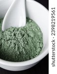 Small photo of Green bentonite clay powder in a bowl. Clay texture close-up. Diy mask and body wrap recipe. Natural beauty treatment and spa.