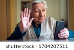 Small photo of Authentic shot of a happy grandmother is making a selfie or video call to relatives with a smartphone at home. Concept of technology, modern generation,family, connection, authenticity