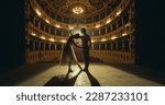 Small photo of Cinematic shot of Young Couple of Classical Ballet Dancers Performing on the Stage of Classic Theatre with Dramatic Lighting. Male and Female Dancers Rehearse their Performance Together Before a show