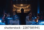 Small photo of Back View Cinematic shot of Conductor Directing Symphony Orchestra with Performers Playing Violins, Cello and Trumpet on Classic Theatre with Curtain Stage During Music Concert