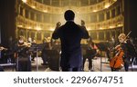 Small photo of Back View of Professional Conductor Directing Symphony Orchestra with Performers Wearing Medical Masks, Playing Violins, Cello and Trumpet on Classic Theatre with Curtain Stage During Music Concert