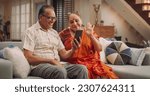 Small photo of Elderly Couple Using Smartphone for Video Call at Home: Connecting with Family, Sharing Stories, and Celebrating Special Occasions. Cherishing Precious Moments Together. Medium Shot.