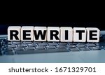 Small photo of concept word rewrite on cubes against the background of laptop keys