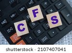 Small photo of CFS (Certified Fund Specialist) - acronym on wooden cubes on the background of a calculator. Business concept