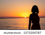 woman silhouette is watching at sunrise or sunset in the sea at the beach