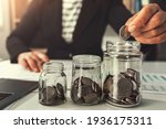 Small photo of saving money with hand putting coins in jug glass concept financial