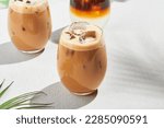 Assorted iced coffee on white concrete background with palm shadows. Minimal composition with cold summer drinks: espresso tonic, ice moccachino and latte. Summer composition for coffee menu