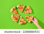 Small photo of American pizza with salami, pepperoni, and jalapeno on a bright green background, featuring hard shadows and minimalist style. A female hand grabbing a slice. Perfect for a casual meal or to-go.