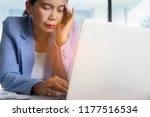 Small photo of Headache Business Woman Working on Laptop in the Office, Soft focus. Thoughtful officer put her hands on head for relax. Jaded, Toilsome, Exhausted Worker in workplace. Fatigue and fail concept