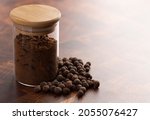 Small photo of Jar of Ground and Whole Allspice on a Dark Wooden Kitchen Counter