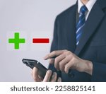 Businessman using smartphones show plus and minus signs. Concept of opposites, decisions, and uncertainty. Positive or Negative Business Choices Analysis of advantages and disadvantages Comparison
