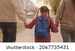 Small photo of mother and father hold a little schoolgirl with a backpack by the hand, happy family, walk through schoolyard in fall, mom, dad and kid with bag over their shoulders, accompany child to first grade