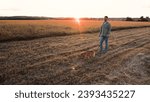 Small photo of Man walks cute cocker spaniel dog on leash in field with mown grass at sunset light owner rests walking red spaniel dog in rural park man with dedicated spaniel dog in country park on weekend