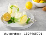 Traditional lemonade with lemon, mint and ice in a glass with metal straw on a gray concrete background. Refreshment summer drink. Copy space