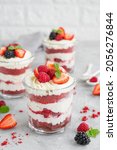 Small photo of Red Velvet cake trifle with fresh berries in a glass jar on a gray concrete background. Dessert for Valentine's Day. Copy space