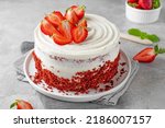 Red velvet cake with fresh strawberries. Festive layered cake from red sponge cakes and cream cheese frosting, American cuisine