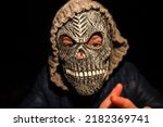 Small photo of Defocus Halloween people. Person in grim reaper mask standing on black background. Dark night mood, nightmare. Halloween horror. Skull ghost. Hands frame. Grim reaper. Out of focus.
