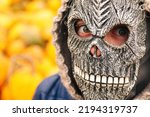 Small photo of Defocus Halloween people portrait. Person in grim reaper mask standing on yellow pumpkin background. Halloween horror. Skull ghost. Grim reaper. Skull mask. Halloween portrait. Out of focus.