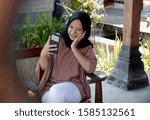 Small photo of Magelang, Indonesia. Isma is sitting while absorbing selfie with her latest smartphone on October 9, 2019 in Magelang, Central Java, Indonesia.