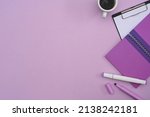 Top view notebook, clipboard and coffee cup on purple background with copy space.
