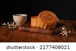 Small photo of Traditional Chinese mooncakes with cup of tea and decorating with dried flower on wooden table