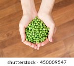 Woman's hands holding green peas. Heart shape from peas