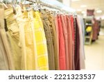Trousers on hangers - clothing rental or reselling concept. Thrist shopping or seconhand store concept. Clothes stall against blurred store background with copy space