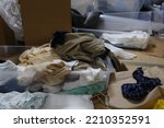 Small photo of A dirty room with a lot of clothes and unused items.