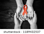 AID red ribbon in hand on a black wooden background, a symbol of the fight against HIV, AIDS and cancer. concept of helping those in need. black and white.