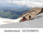 Two mountaineers standing on glacier and looking towards Grossglockner High Alpine Road and mountain panorama in Glockner Group, Austria