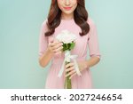 Attractive young woman holding bouquet of white roses isolated over green pastel background