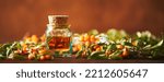 Small photo of Glass bottle with sea buckthorn oil berries and sea buckthorn branches on wooden background. Long wide banner