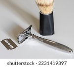T-shaped metal chrome razor with replaceable blades. A safety razor whose blade is inserted inside and clamped on both sides on a t-shaped razor. White background and minimalism