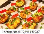 Small photo of Twice-baked potatoes stuffed with mushed smooth potato pulp and sprinkled with fried crispy bacon and snipped chives. Stuffed Jacket Potatoes. Food decorated with Polish flag skewer
