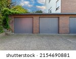 Small photo of Modern parking garage in residential brick house for cars with grey roller shutters on gates. Closed doors in garages.