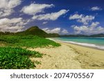 Small photo of serangan beach. Panorama of Indonesia's tropical beaches with green grass, white sand, hills, clouds and blue skies and clear water.