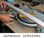 Small photo of setting the angle on the basis of a circular machine for trimming the edge of a wooden skirting board, working on a miter saw with wooden material in a carpenter's workshop