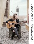 Small photo of Young woman songwriter playing spanish guitar in outdoor and singing.