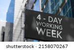 Small photo of 4 - Day working week on a black city-center sign in front of a modern office building