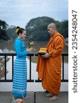 Small photo of Women make merit offer food and put it in monk alms bowls with monks in rural areas according to the beliefs of Buddhism on the ancient iron bridge in Chiang Mai, Thailand. It is Asian traditional.