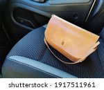 A leather handbag that is obviously lying on a passenger seat.