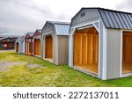  American wooden sheds with metal roof and garage sliding door style in display. Simple single-story roofed structure in a backyard or on an allotment that is used for storage, hobbies, or workshop. 