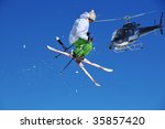 a skier in green and white performing a tele-heli, being filmed from a crew in a helicopter equipped with a front mounted steady cam